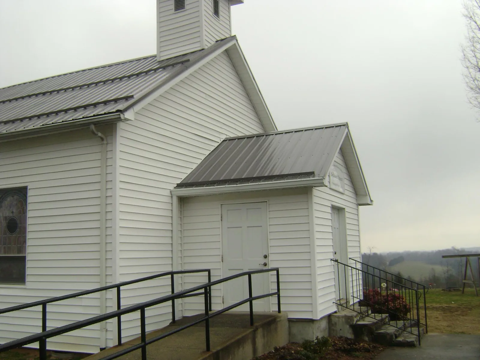 Gray metal roof on a white clapboard church with a steeple in Milledgeville