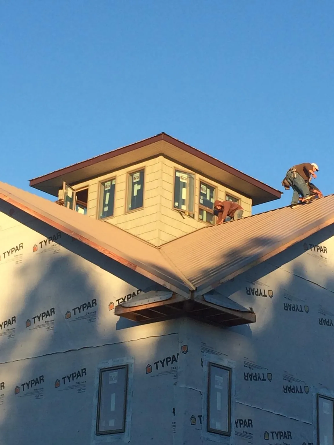 Roofers working around a rooftop cupola on a new metal roof at sunset — Roof Waterproofing in Milledgeville by Roofing Brothers